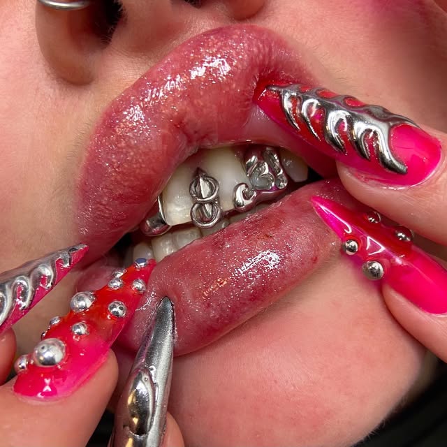 Pink-nailed fingers revealing silver tooth gems